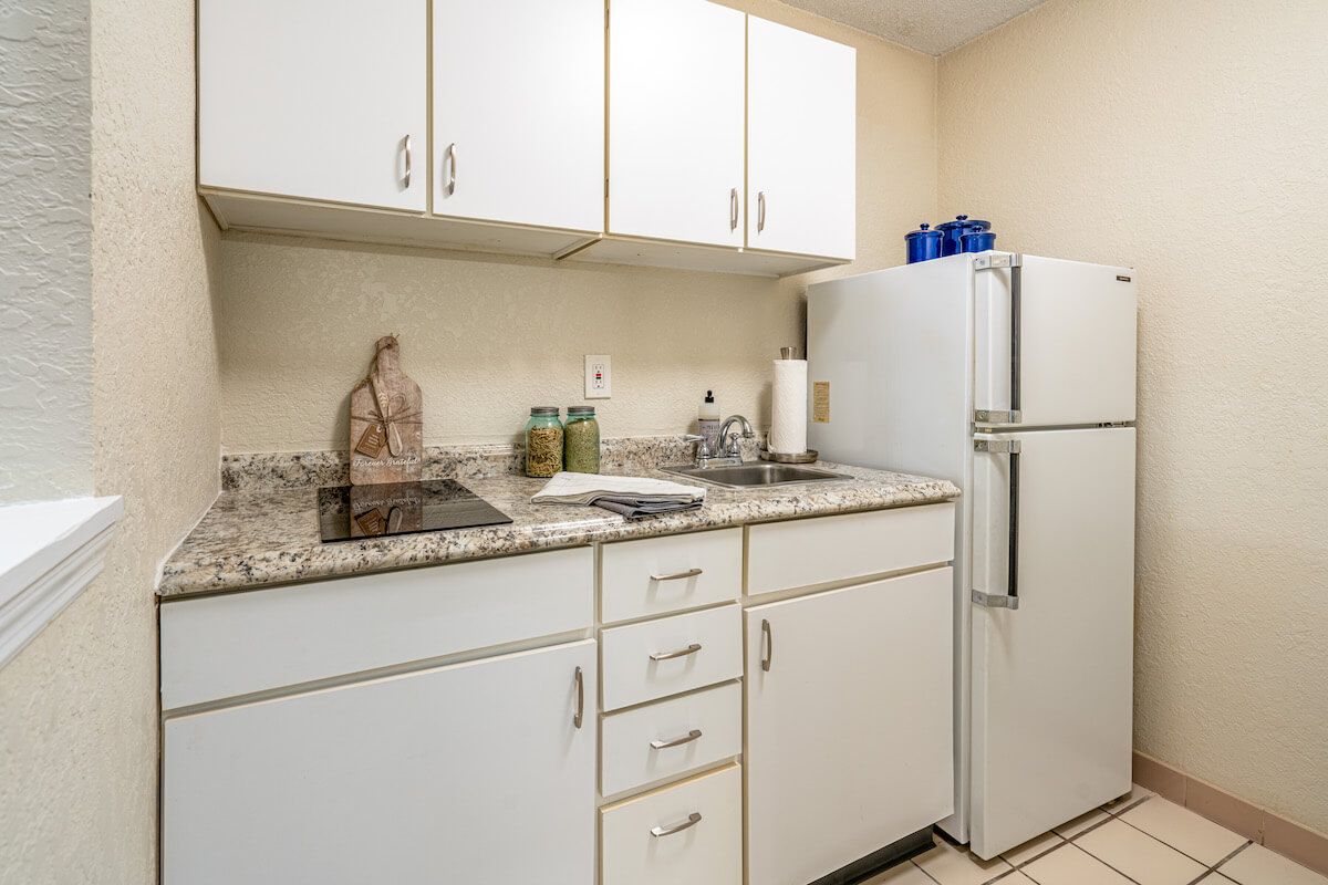 A compact kitchen with white cabinets and a refrigerator.