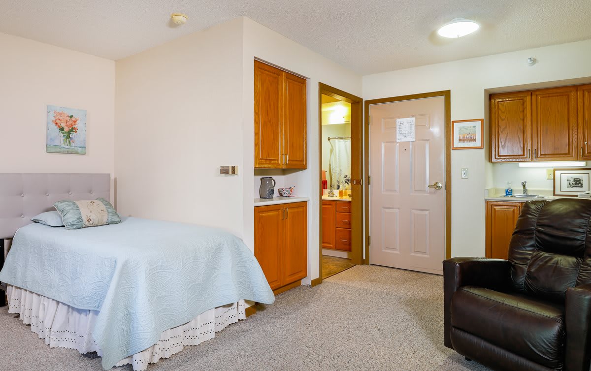 Cozy bedroom with a view of an adjoining bathroom and wooden cabinetry.