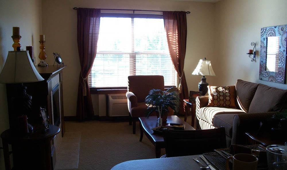 A cozy living room with a window, chairs, and a table.