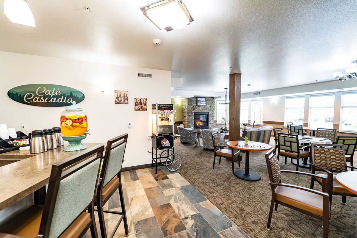 A cozy cafe interior with seating, tables, and a beverage dispenser.