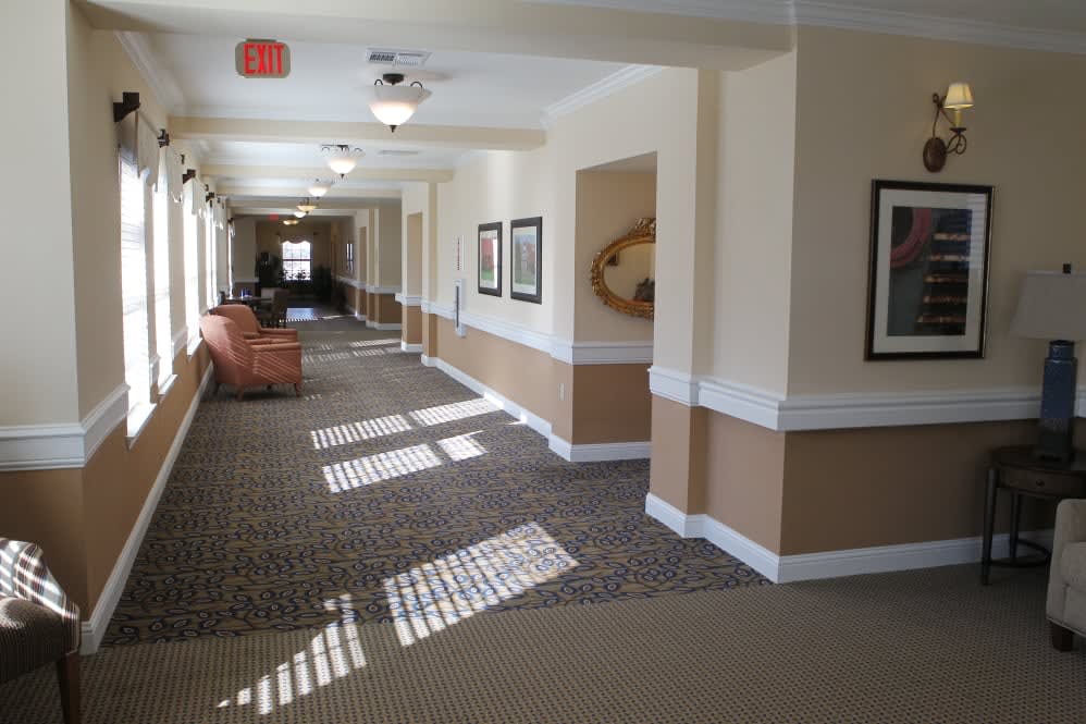 A well-lit hallway with carpeted floors and wall decorations.