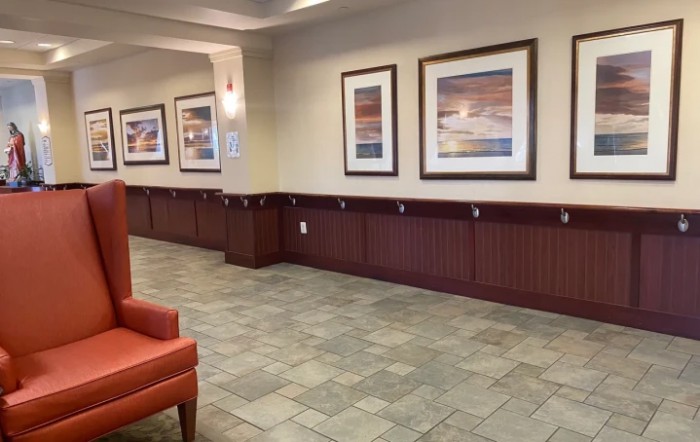A clean and well-lit hallway with framed artwork and tiled flooring.