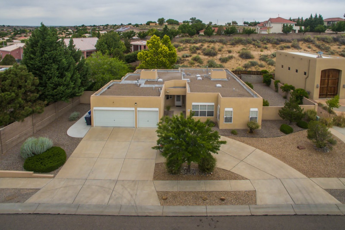 Aerial view of a single-story house with a flat roof in a suburban desert area.