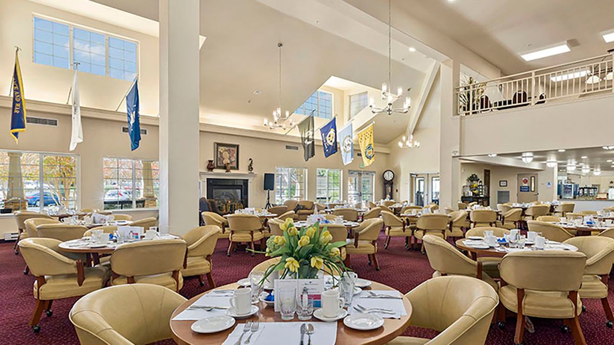 A well-decorated dining room with elegant tables, chairs, and chandeliers.