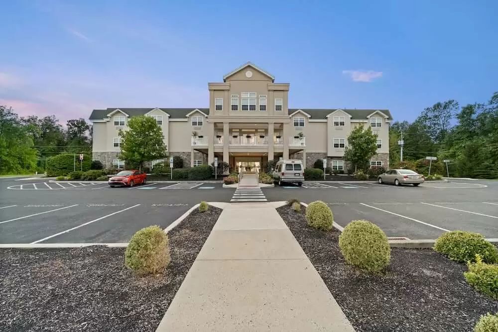 A hotel building with a large entrance and a surrounding parking lot.