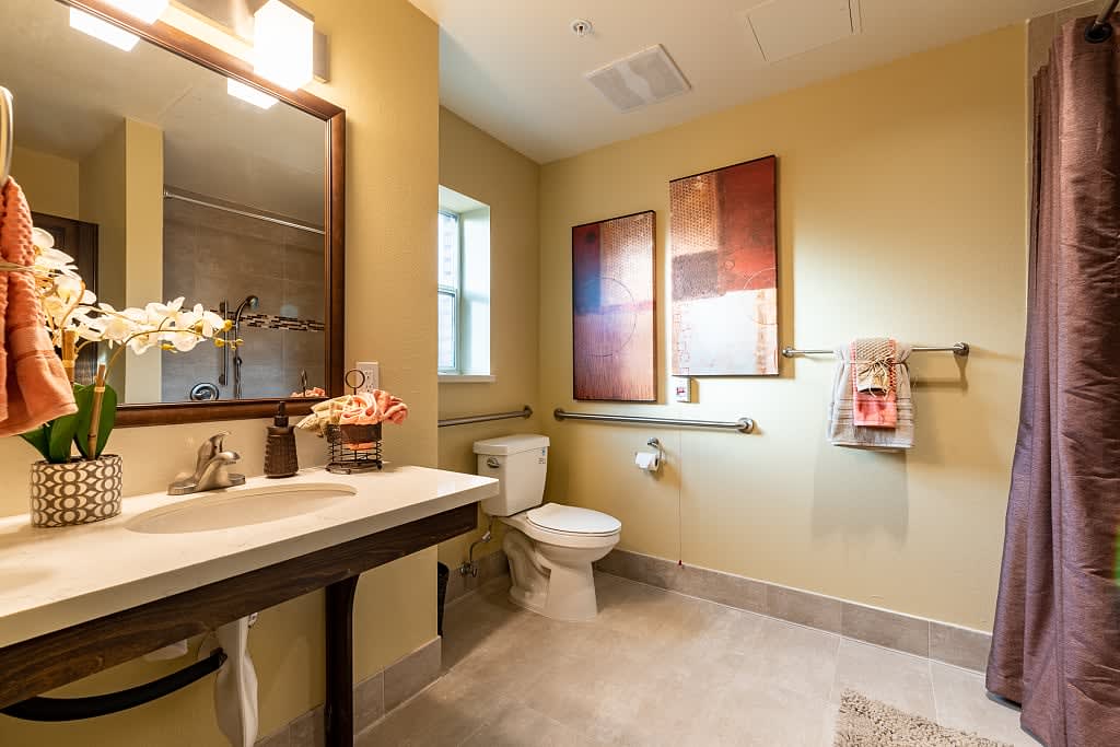 A modern bathroom with decorative artwork on the walls, featuring a sink, mirror, and toilet.
