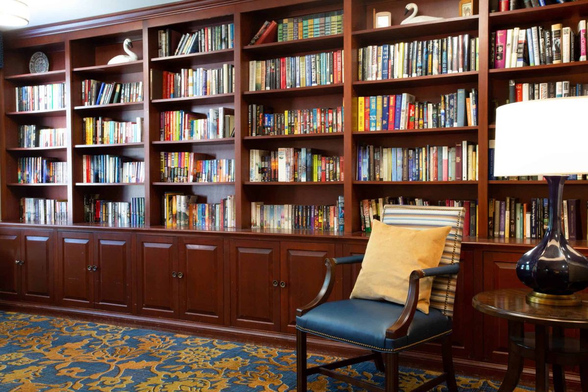 A cozy reading nook with a wooden bookshelf filled with books and a comfortable chair.