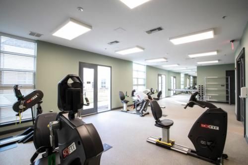 A modern gym equipped with exercise bikes and treadmills, featuring large mirrors and ample lighting.