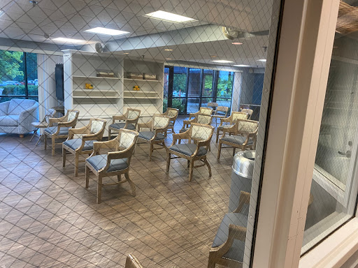A spacious and empty dining area featuring several tables and chairs, with natural light coming through the windows.