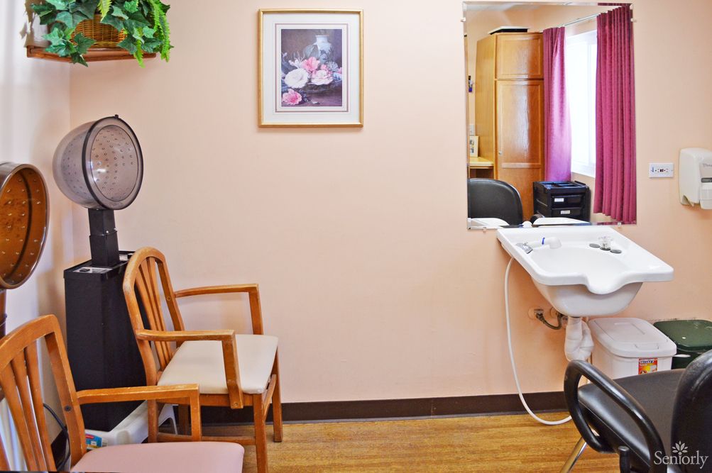 A cozy hair salon interior with a waiting area, chairs, and a sink.