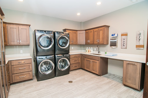 A modern laundry room featuring stacked washer and dryer units along with wooden cabinetry.