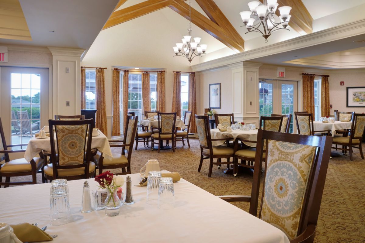 Elegant dining room with neatly arranged tables and chairs under warm lighting.