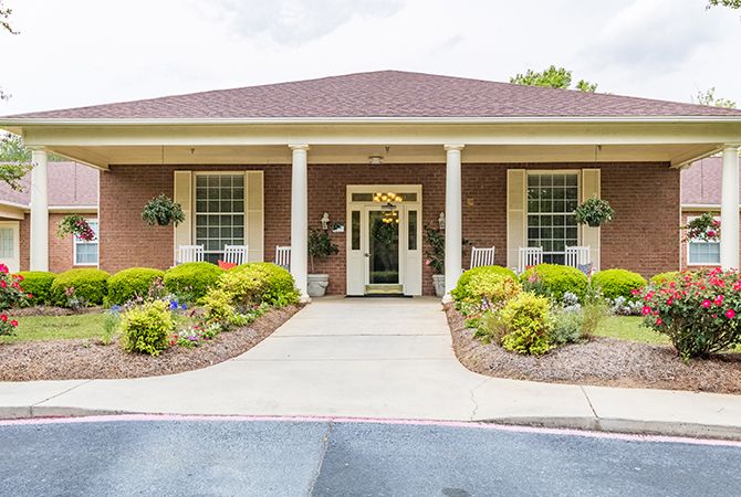 A well-maintained building entrance with a brick exterior and landscaped front yard.