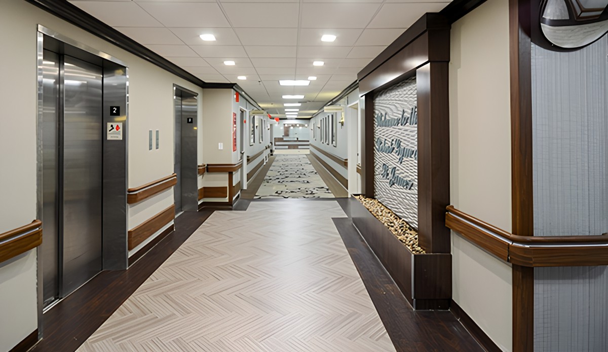 A modern hospital hallway with elevators and a well-lit corridor.