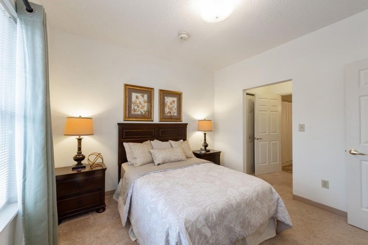 A cozy bedroom featuring a neatly made bed flanked by two nightstands with lamps, accented with framed artwork above the headboard.