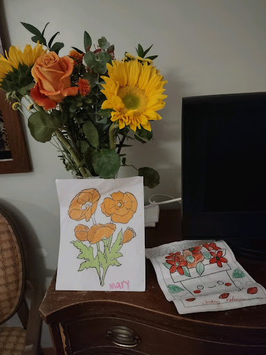 A vibrant display of fresh flowers alongside a colorful artwork of orange flowers and decorative napkins.