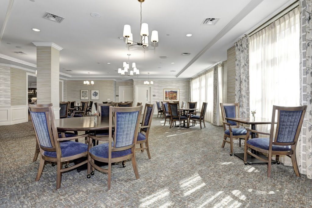 A spacious dining room with elegant furniture and chandeliers.