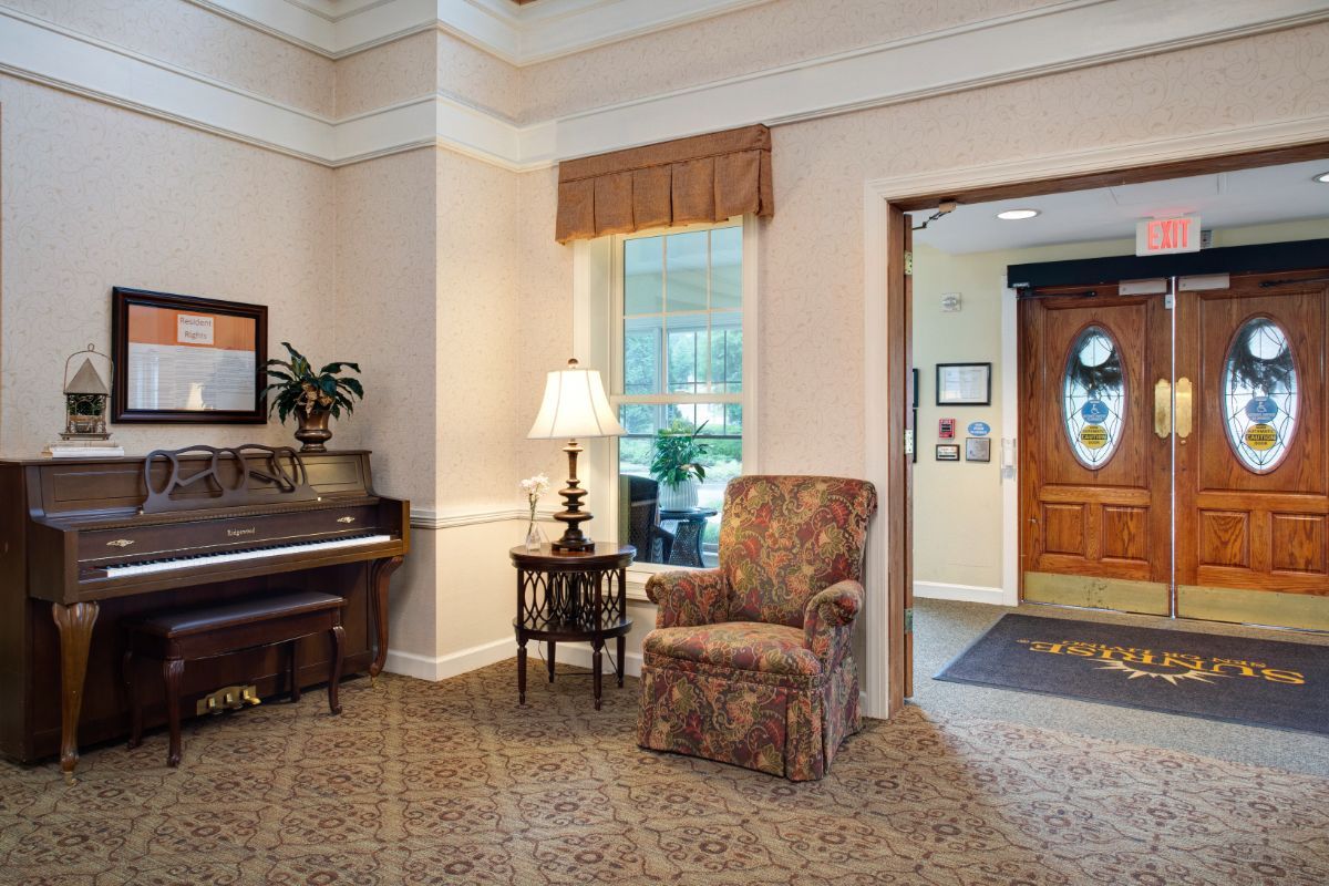 A cozy living room interior with a piano, armchair, and decorative lamp.