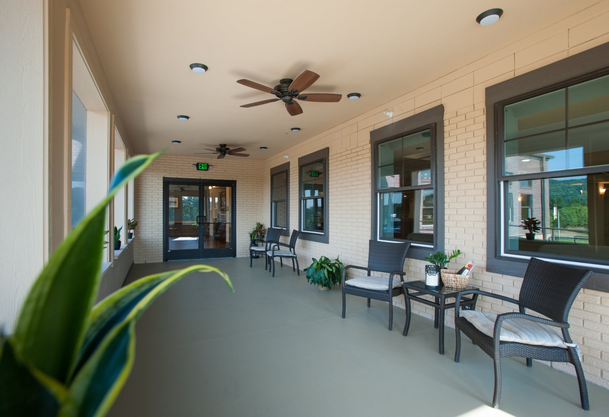 A cozy outdoor porch with seating, ceiling fans, and plants.
