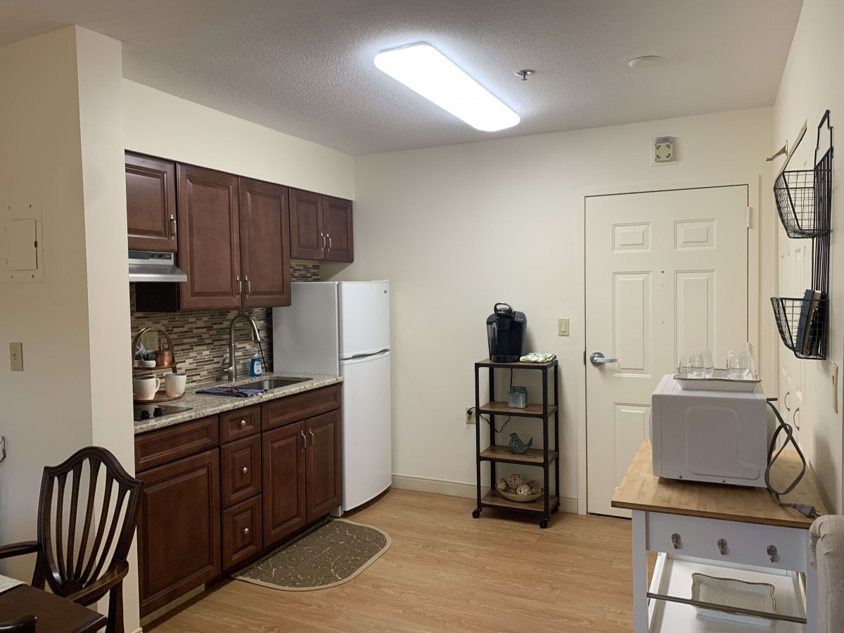 A cozy apartment kitchen with wooden cabinets and a refrigerator.