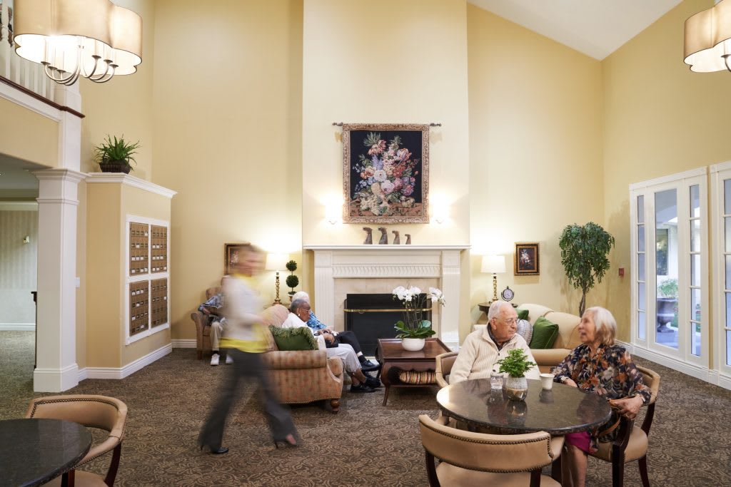 A comfortable common area in a senior living facility where elderly residents engage in conversation and relaxation.