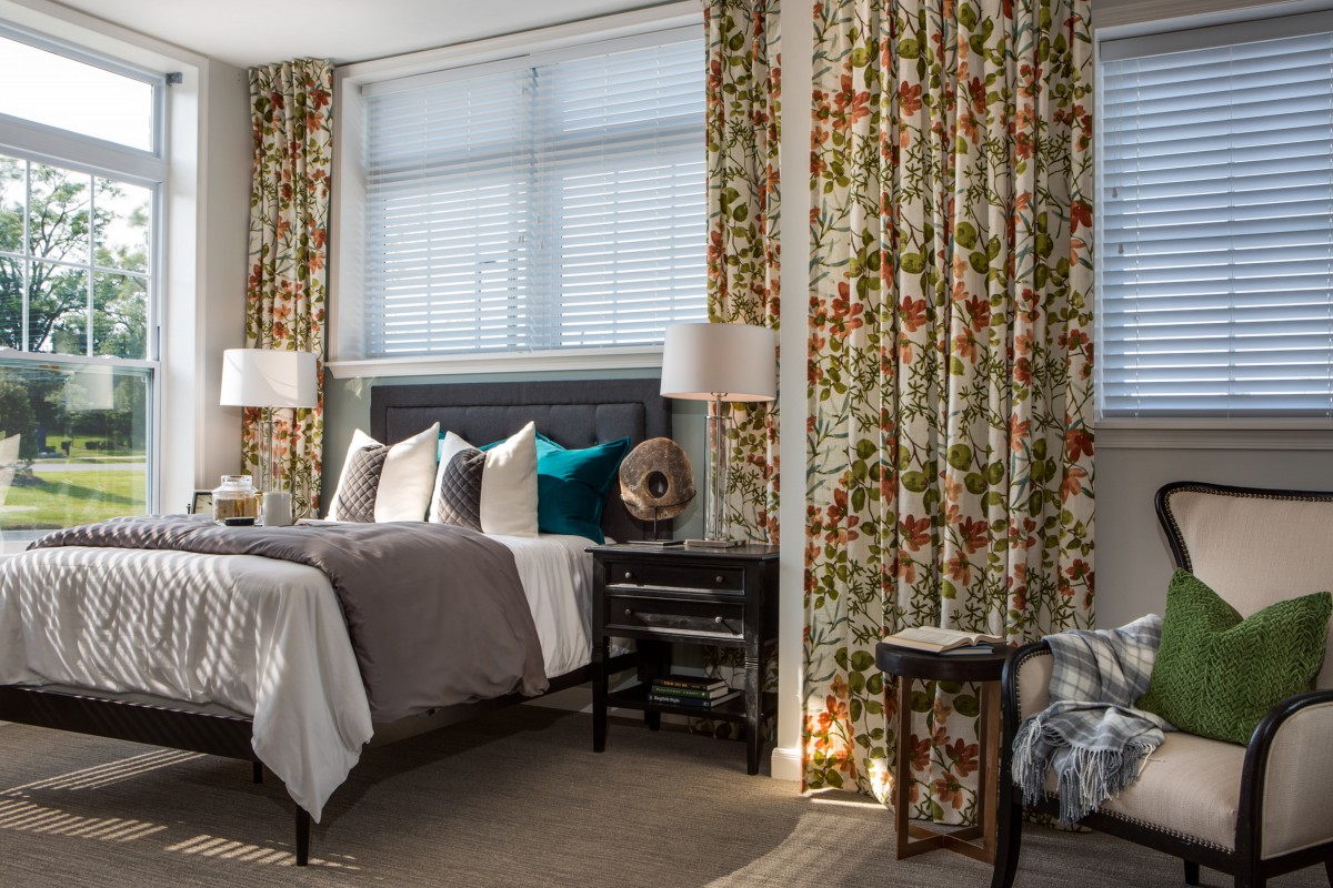 A cozy bedroom with floral curtains, a neatly made bed, and stylish decor.