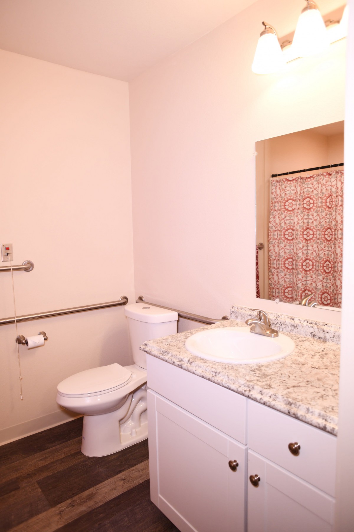 A bathroom featuring a toilet, sink with granite countertop, and a mirror.