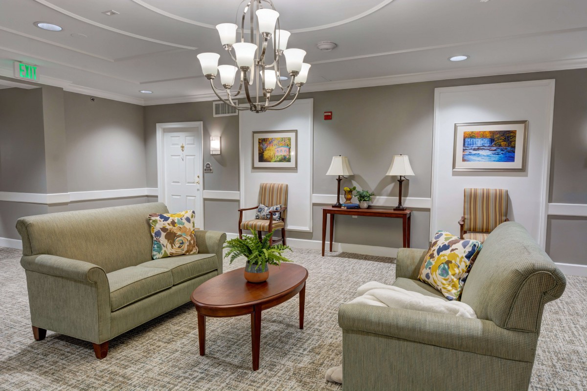 A cozy and elegantly decorated living room featuring comfortable sofas, a wooden coffee table, and a chandelier.