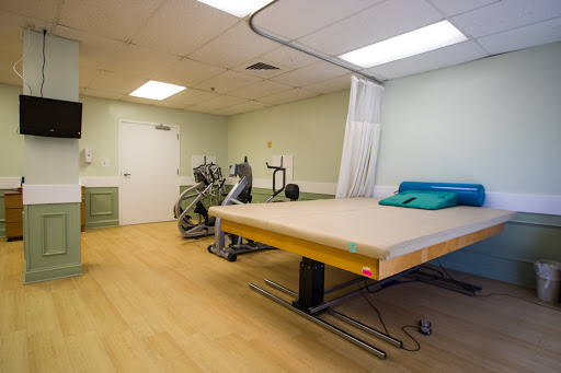 A spacious therapy room equipped with exercise equipment and a treatment bed.