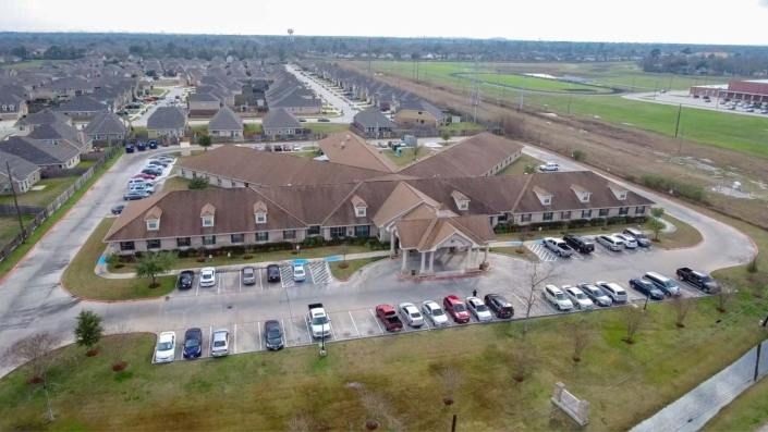 Aerial view of a suburban residential neighborhood with a central building and a parking lot filled with cars.