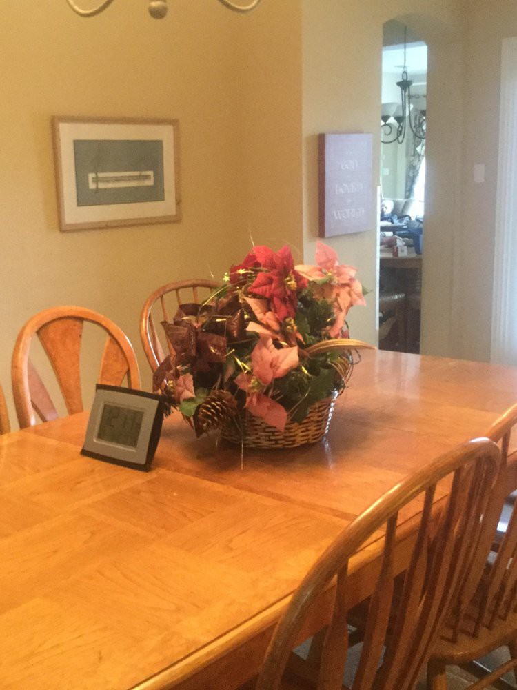 A cozy dining room setup with a wooden table, chairs, and a decorative flower arrangement centerpiece.