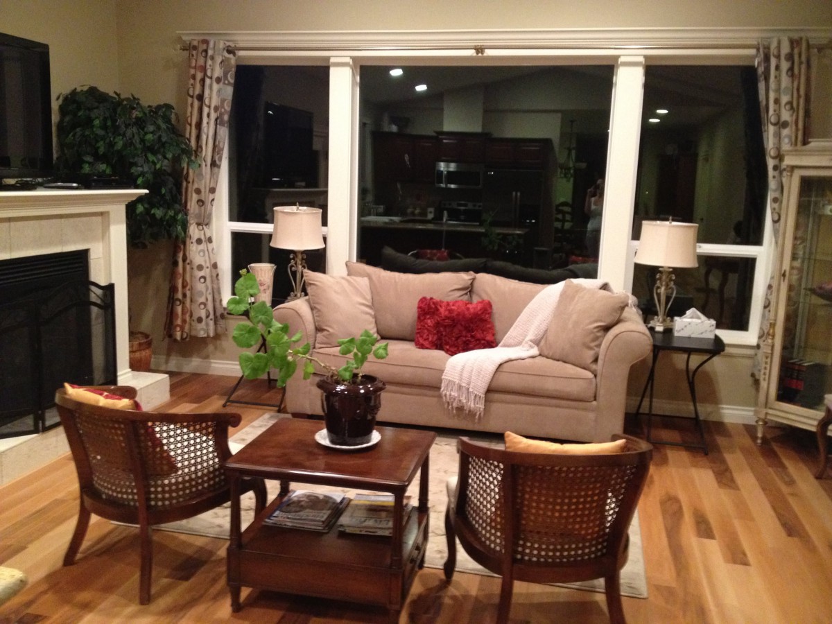 A cozy living room with a beige sofa, two wooden chairs, a coffee table, and decorative lamps.