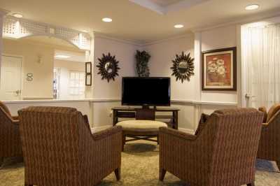 A cozy living room setup with wicker armchairs facing a television, complemented by decorative artwork and plants.