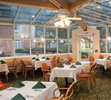 A cozy dining area with tables set for a meal, featuring ample natural light from the glass ceiling.