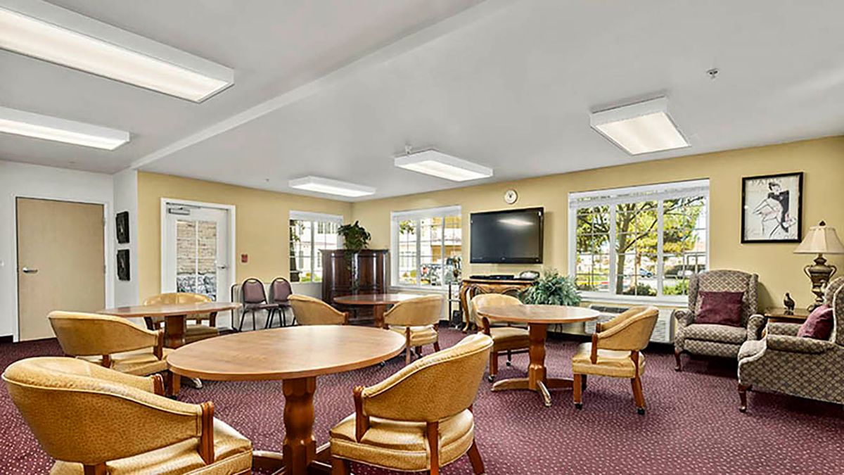 A spacious and well-lit meeting room with tables, chairs, and a television.