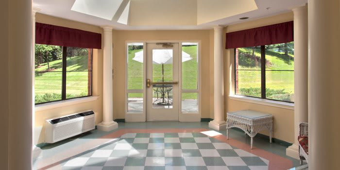 A bright entrance with large windows, a checkered floor, and decorative columns.