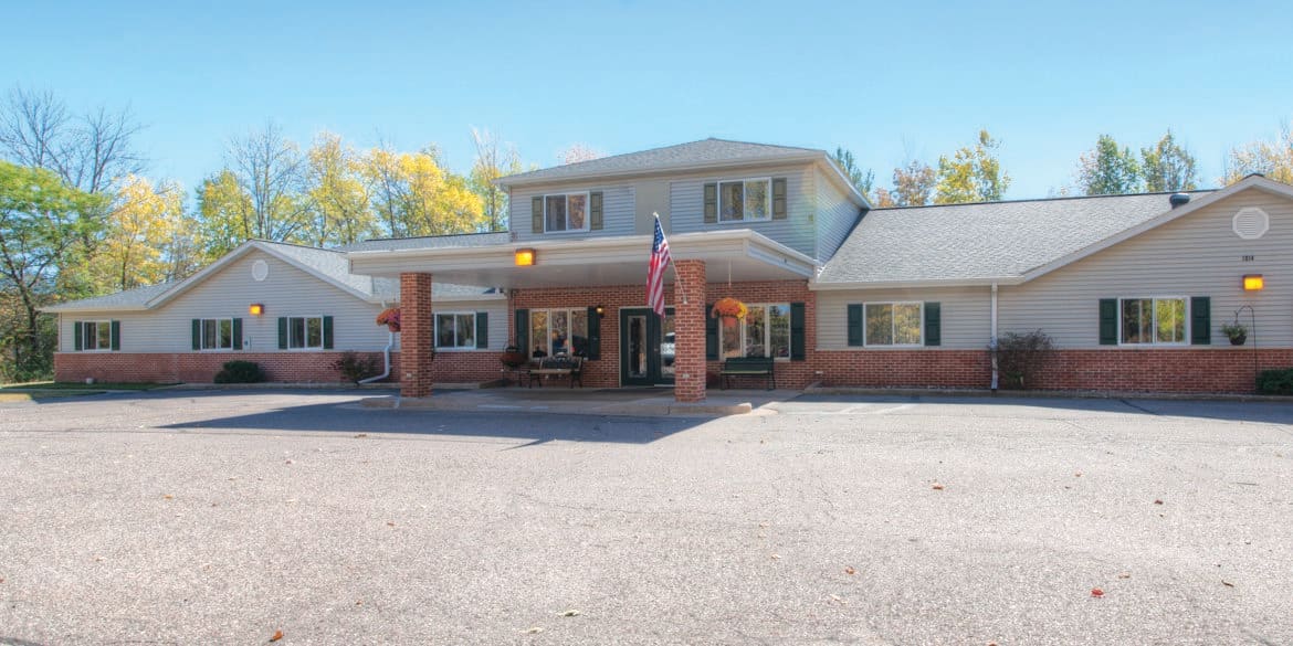 A two-story motel building with a parking lot and an American flag displayed at the entrance.