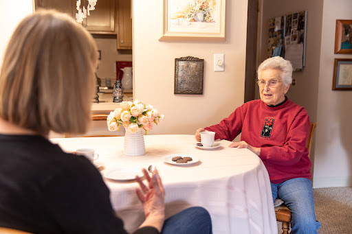 Two women engage in a warm conversation over coffee in a cozy home setting.