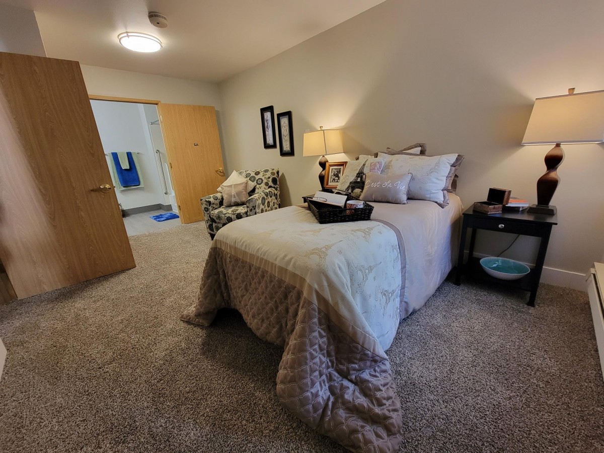 A cozy bedroom with a neatly made bed, nightstands, and a comfortable chair.