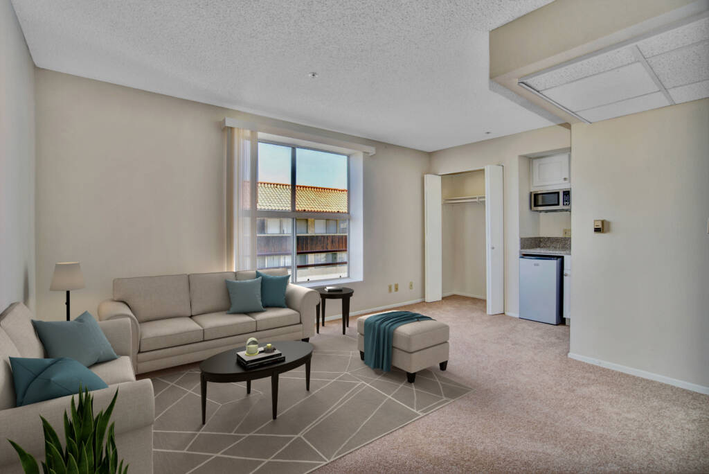 A bright and minimalist living room with a sofa, coffee table, and window providing natural light.