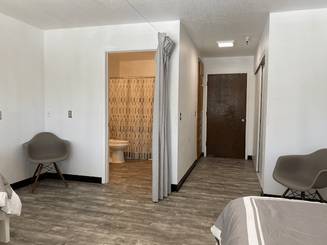 A modern hotel room interior with a visible bathroom entrance.