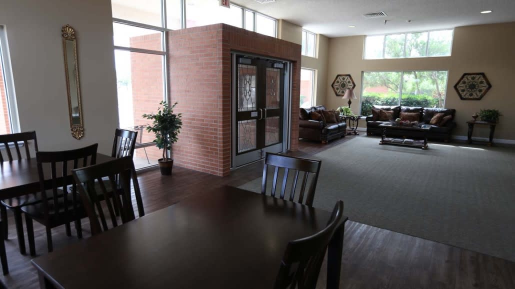 A well-lit lobby area featuring tables, chairs, sofas, and a brick wall.