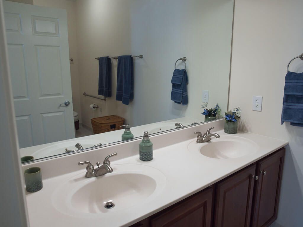 A bathroom with a double sink vanity and a large mirror, decorated with blue towels and small plants.