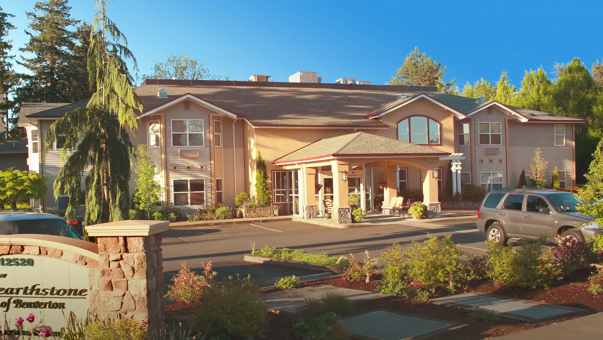 A sunny view of a large residential building with well-maintained landscaping.