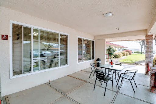 A cozy outdoor patio area with a table and chairs, surrounded by large windows, perfect for relaxation.