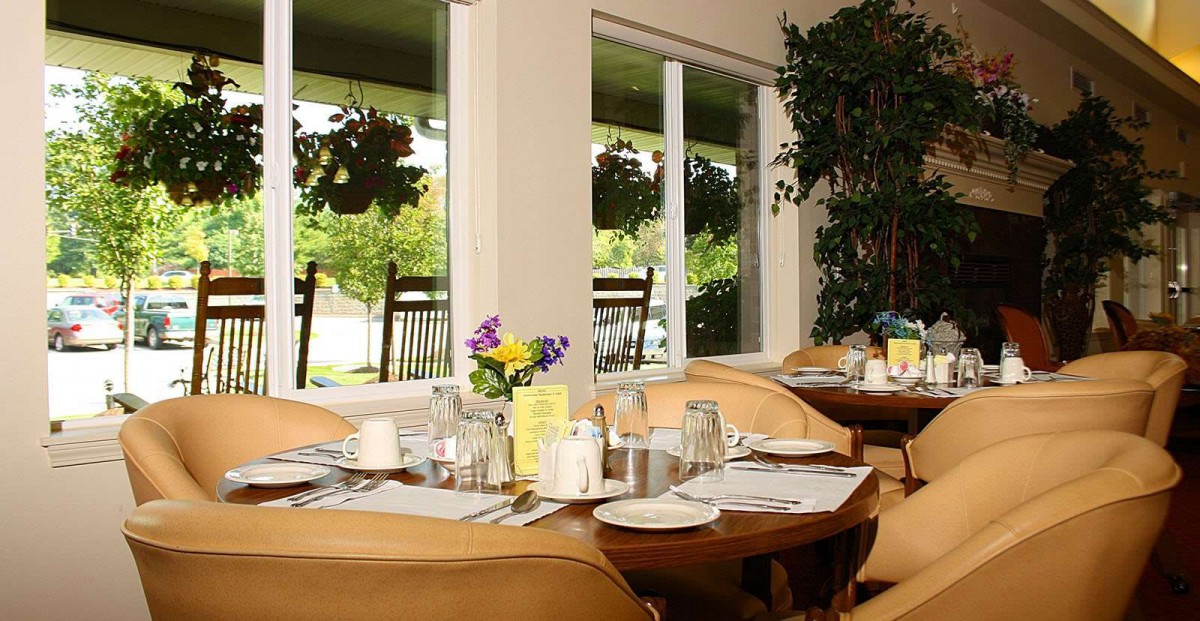 A cozy restaurant interior with neatly set tables and floral decorations by the window.