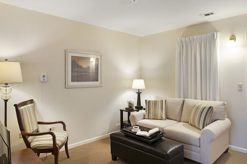 A cozy living room with a sofa, armchair, and ambient lighting.