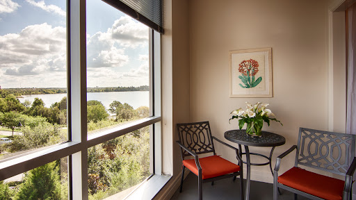 A cozy corner with a view of nature, featuring a small table and chair adorned with fresh flowers.