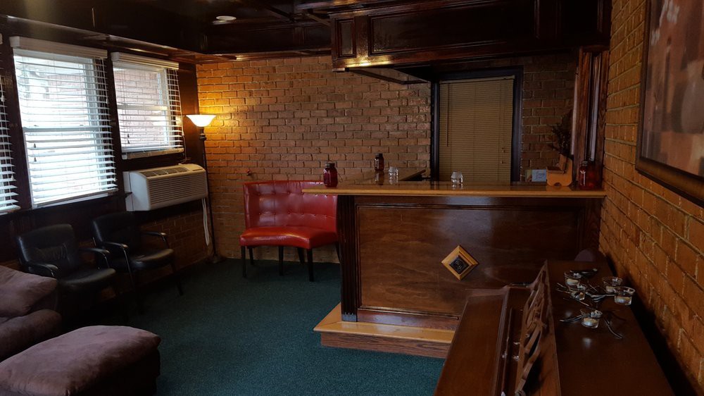A cozy retro-style bar with wooden furniture and brick walls, featuring a small seating area.