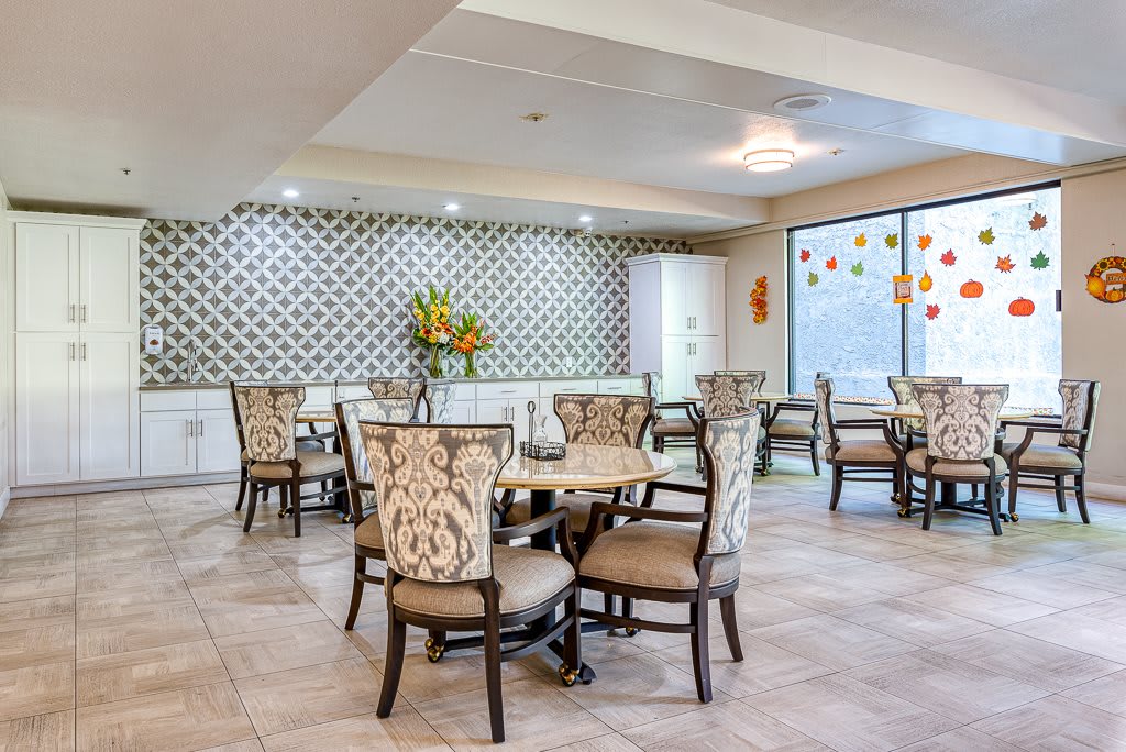 A modern dining area with decorative wallpaper, stylish chairs, and bright lighting.